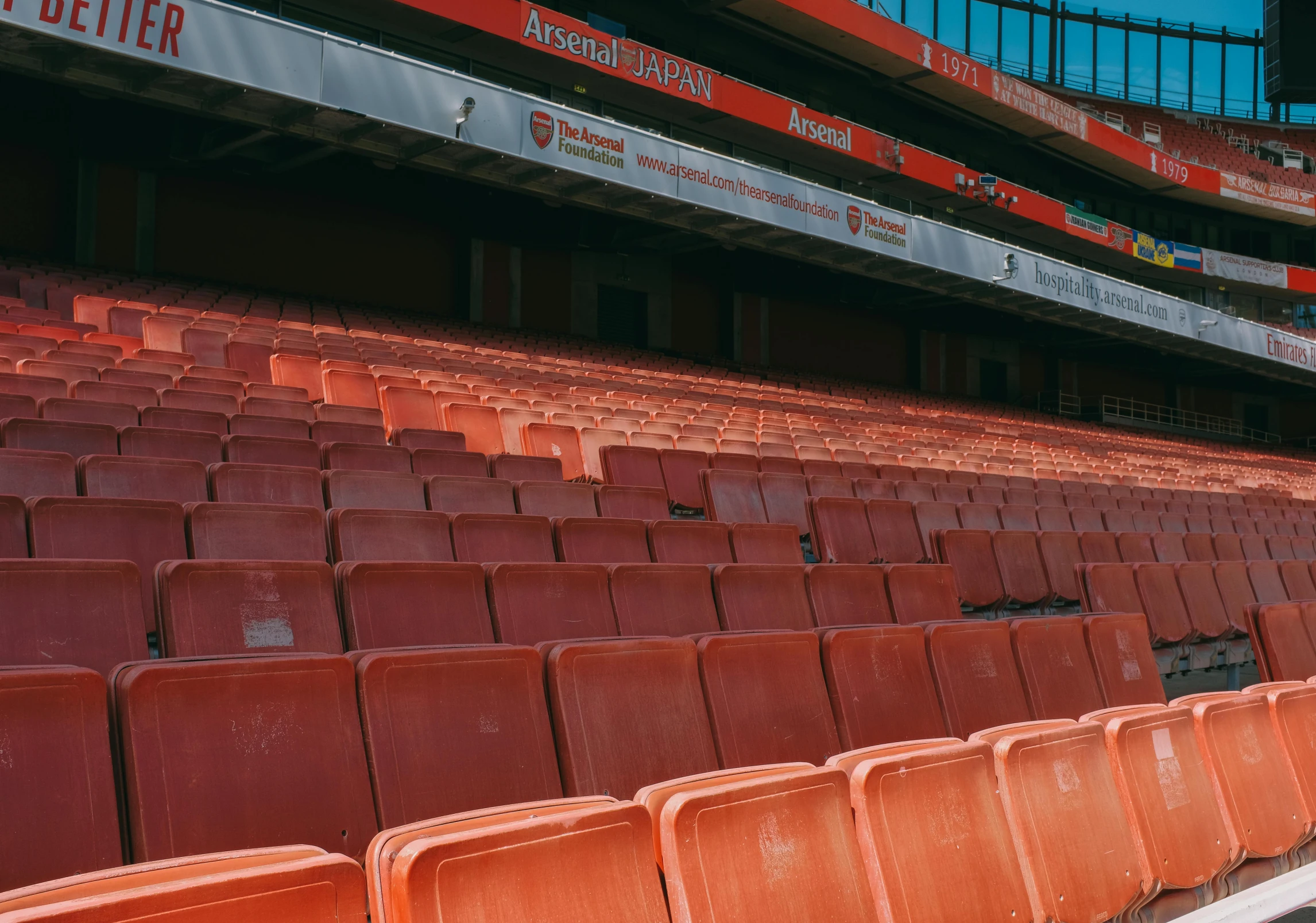 a row of orange seats in a stadium stands alone