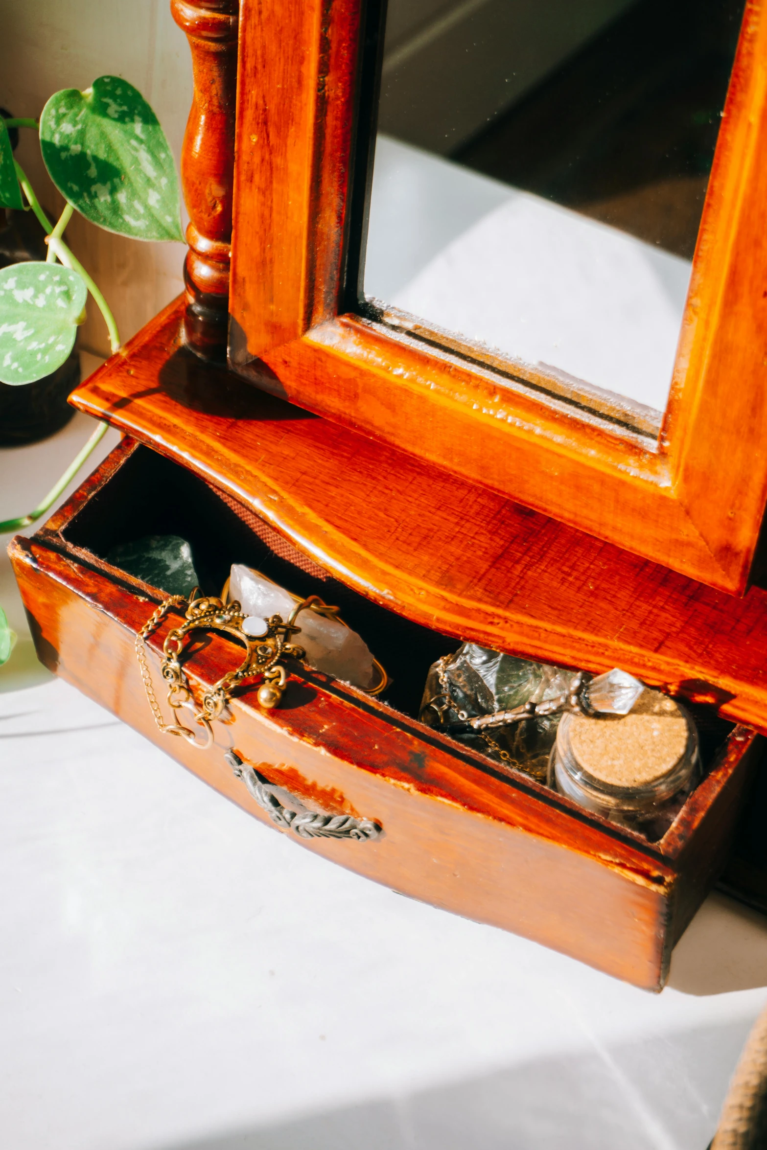 the wooden jewelry box is on the table with a mirror