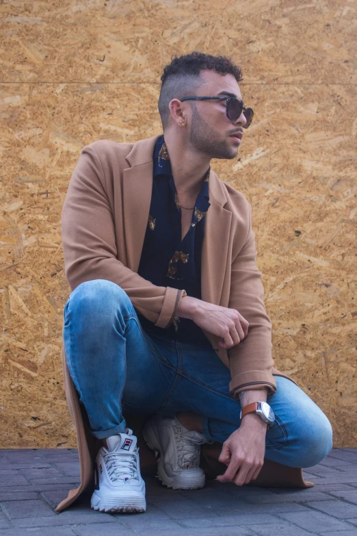 man in brown jacket sitting on the ground with his shoes on