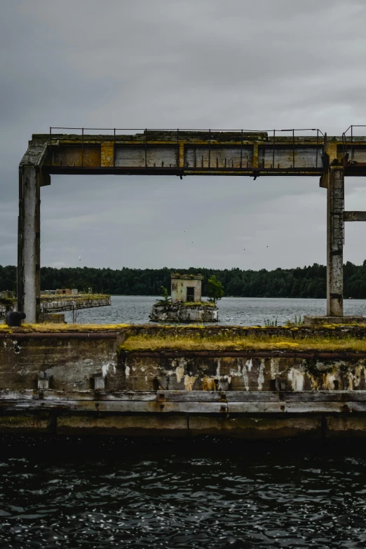 an old bridge sits on the water's edge with a little house in the background