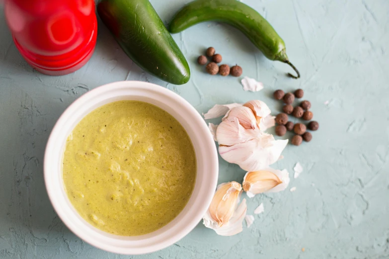 several vegetables are around a small bowl filled with a green soup