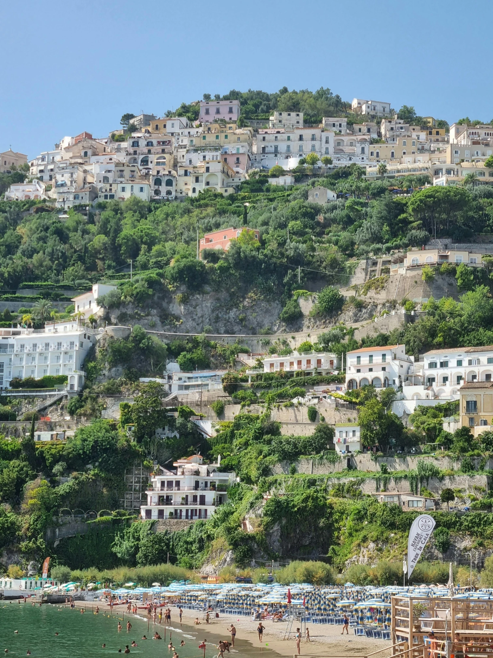 several people walking on a beach with a lot of houses on it