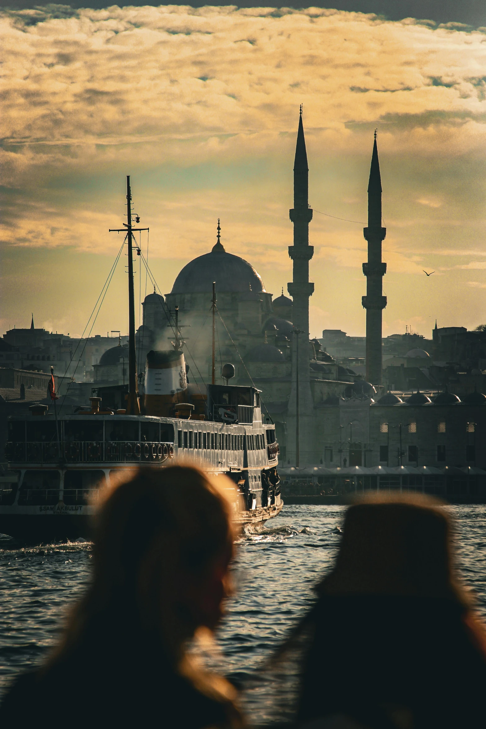 two women are looking at a boat floating in front of an ancient city