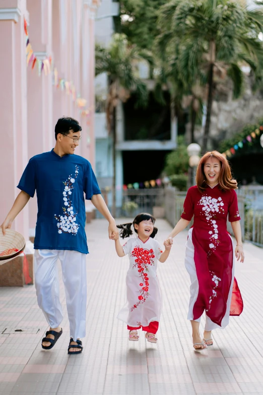 family in asian clothing walking down a city street