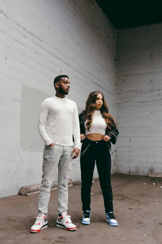 a man and woman standing in front of a white wall