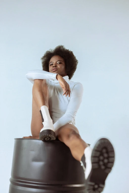 a woman sitting on top of a black trash can