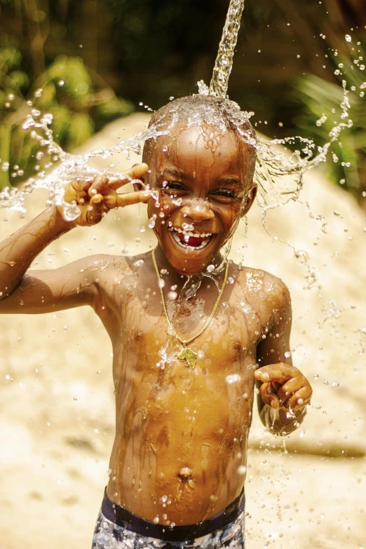 a child splashing from a fountain with a piece of wood on his head