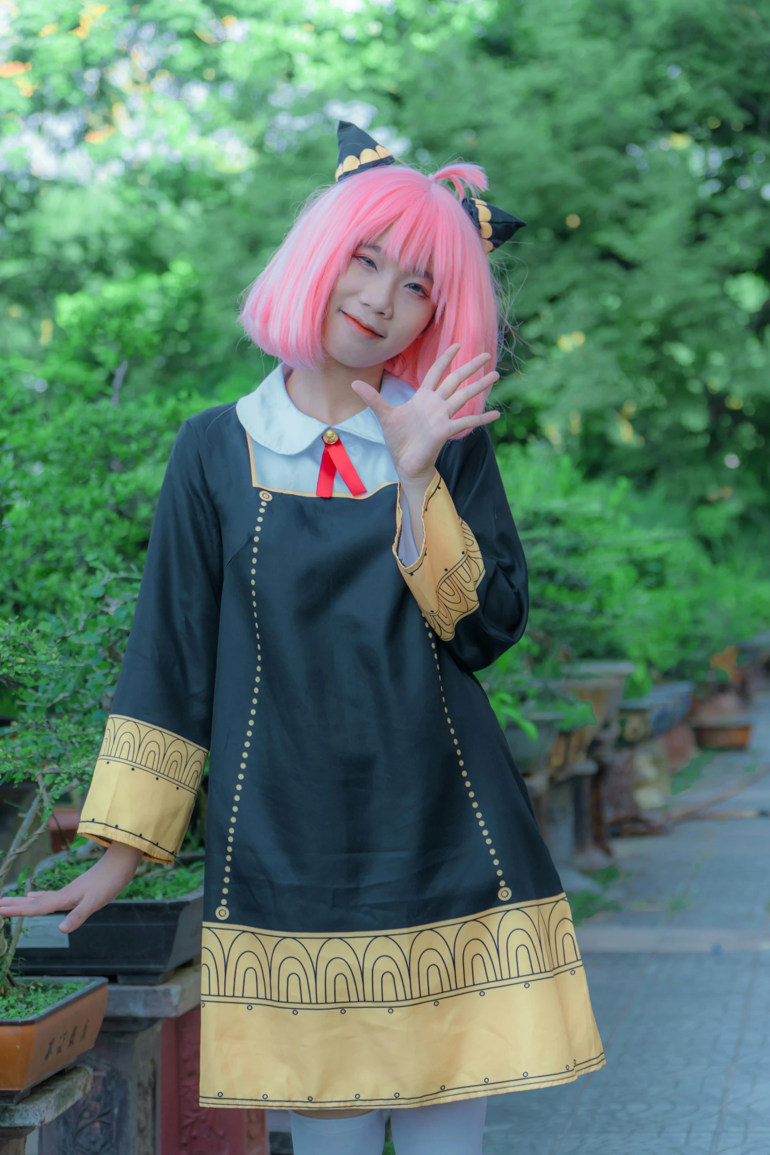 a pretty girl standing next to a garden wearing a black dress