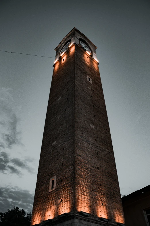 a tall brick clock tower with lights at the top