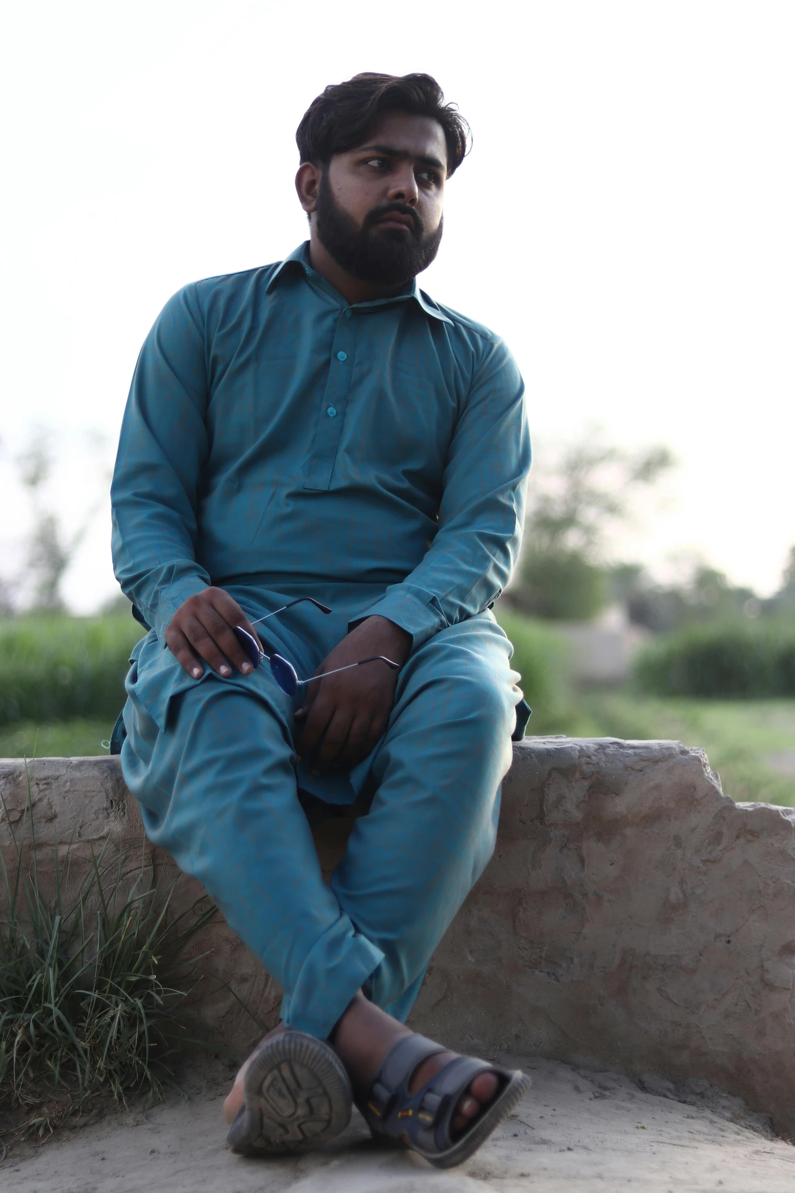 a man is sitting against a stone structure