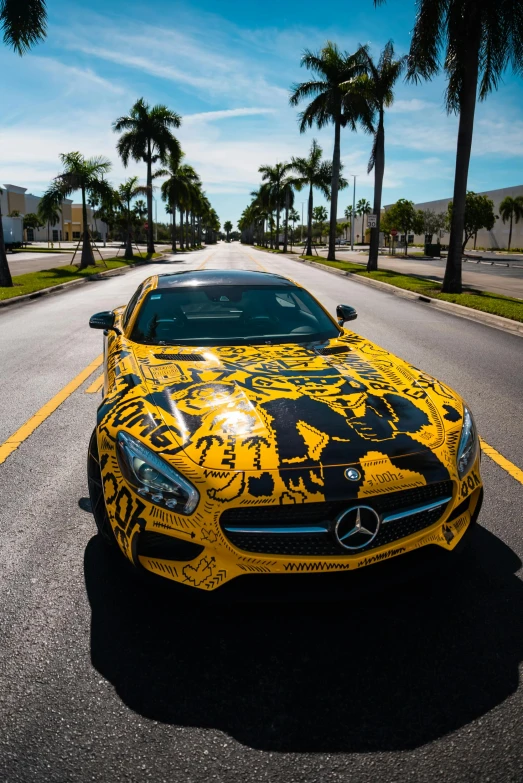 a mercedes sports car with yellow graffiti painted on it's hood