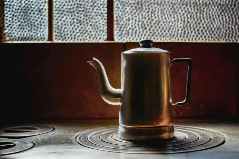 a copper colored kettle sitting on top of a stove