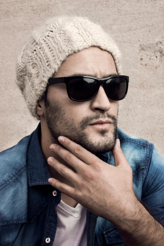 man wearing a beanie and sunglasses stares off into the distance