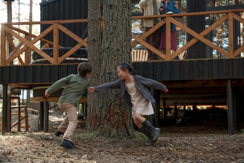 two young children playing in the woods near a tree house