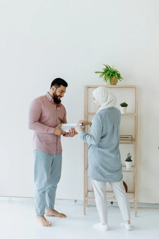 two people standing in front of a shelf with a plant