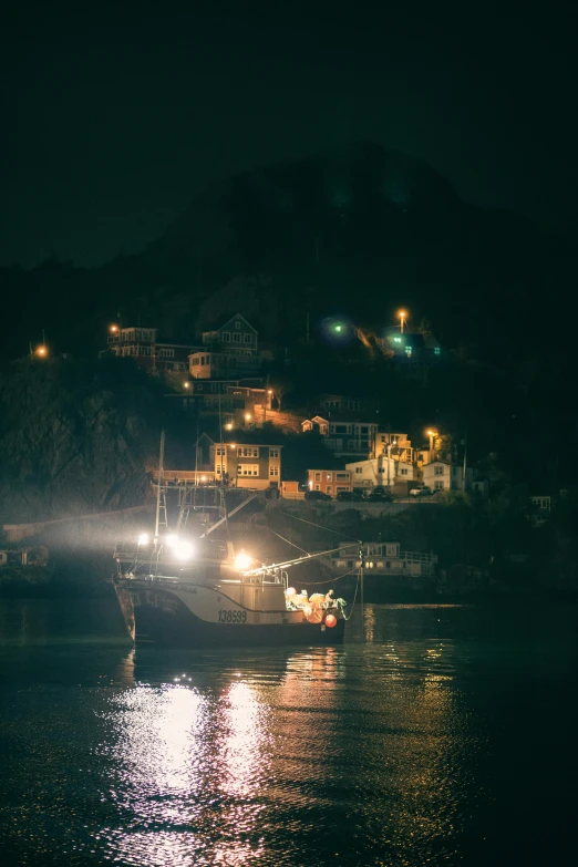 boats floating along a large body of water at night