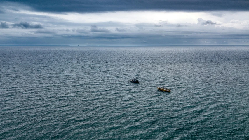 two canoes floating across the water with clouds in the sky