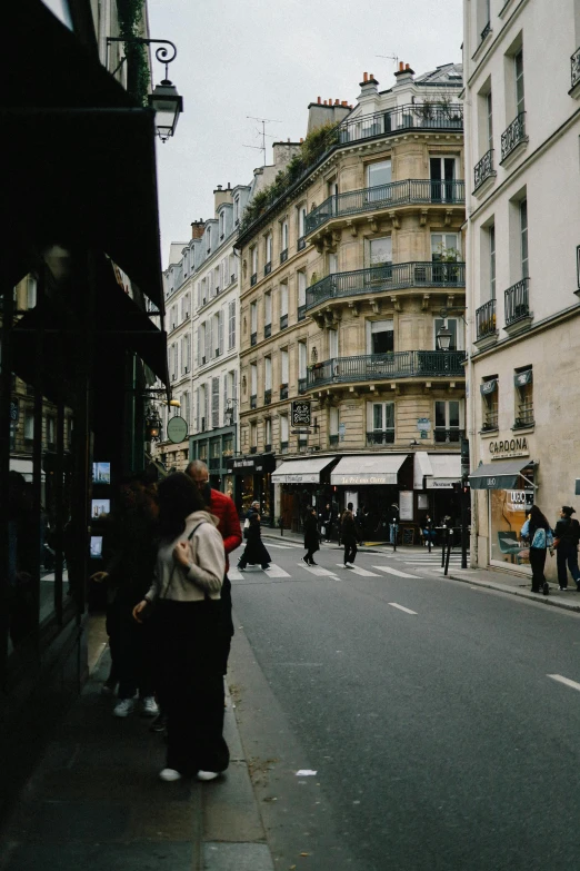 a couple of women walking down a street past tall buildings