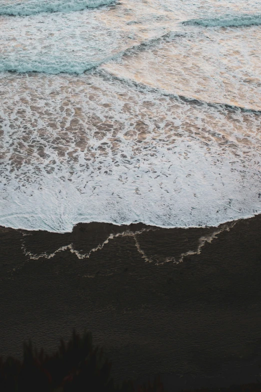 the ocean with waves washing in and sand covered shore