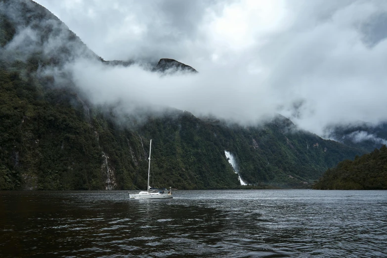 a sailboat travels in between green mountain peaks