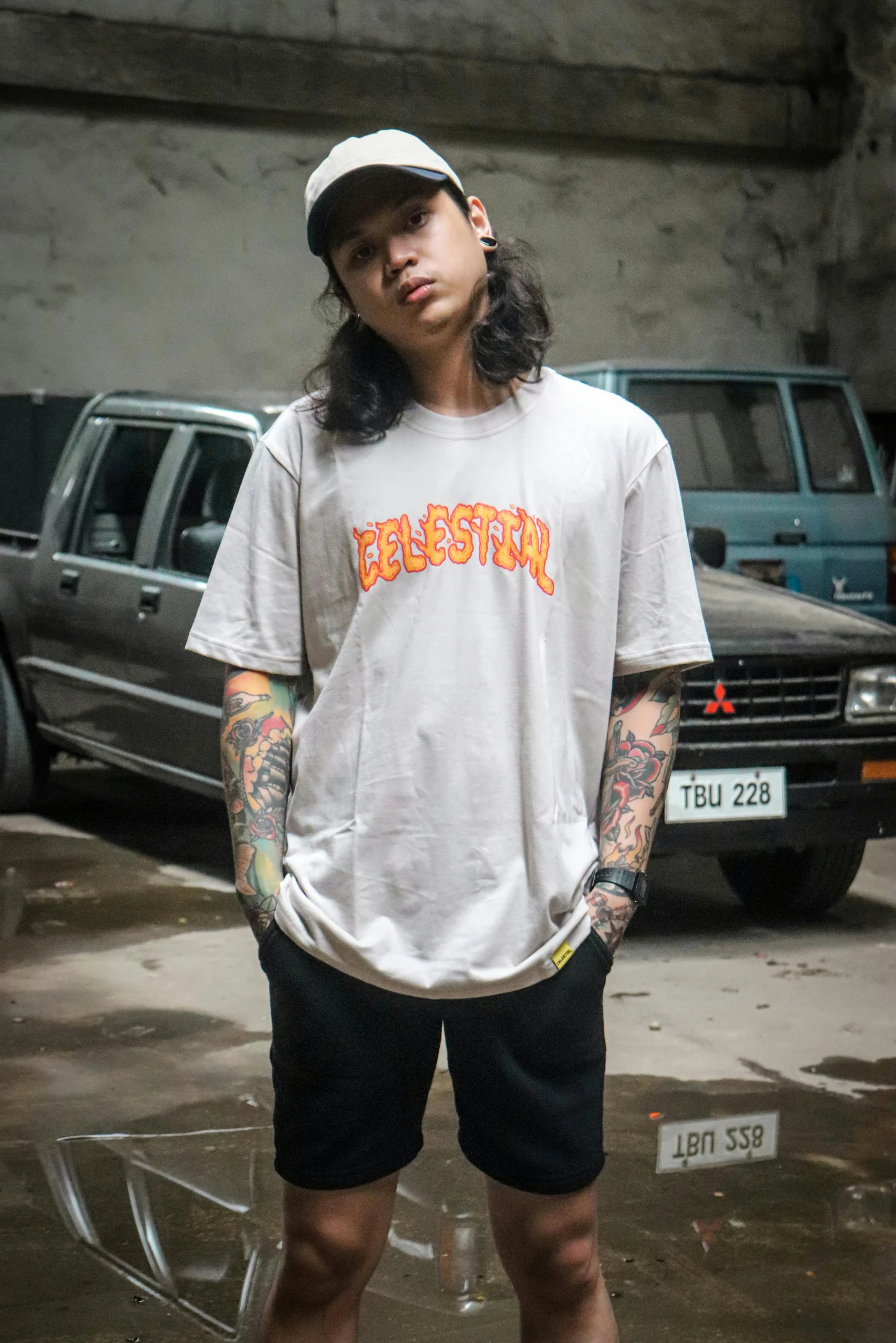 young man standing in parking lot wearing white and orange tattoo