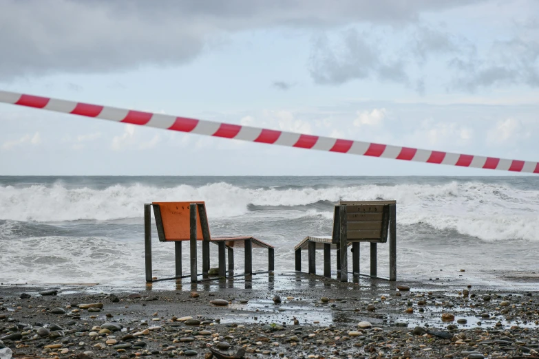 a red and white pole is in the air over two chairs near a body of water