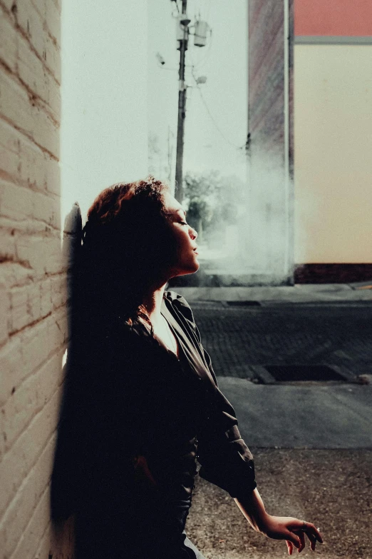 the back of a woman sitting next to a brick building