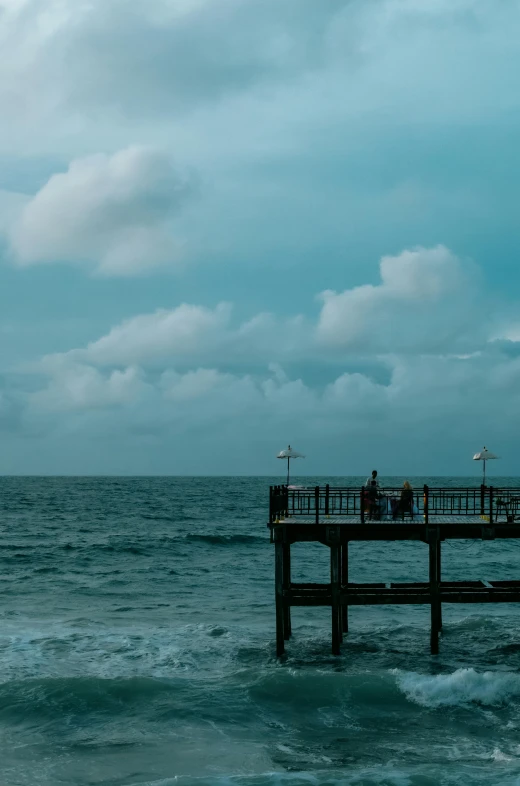 a couple of people are on the dock that is in the middle of the ocean