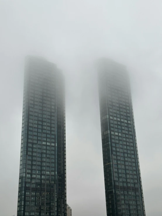 a couple of tall building that are surrounded by fog