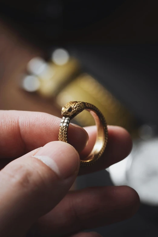 a hand holding up a gold ring on it's finger