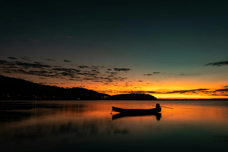 a boat is sitting in the water as the sun sets