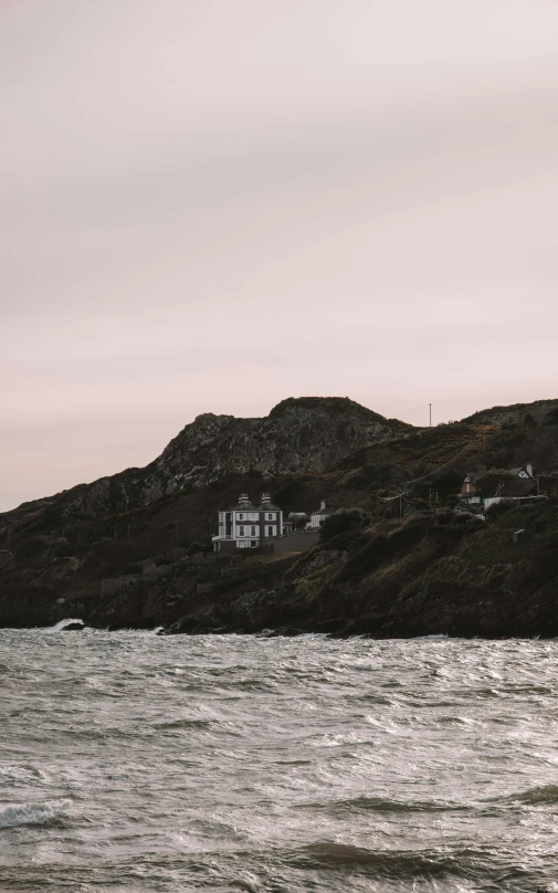 a house perched on top of the mountain above water