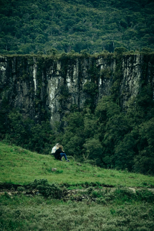 a person sitting on a hill near some tall cliffs