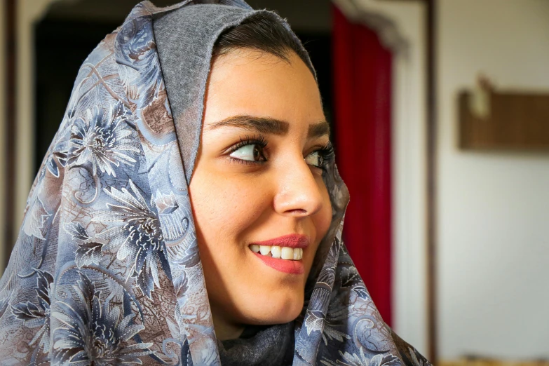 a woman wearing a patterned headscarf smiles at the camera