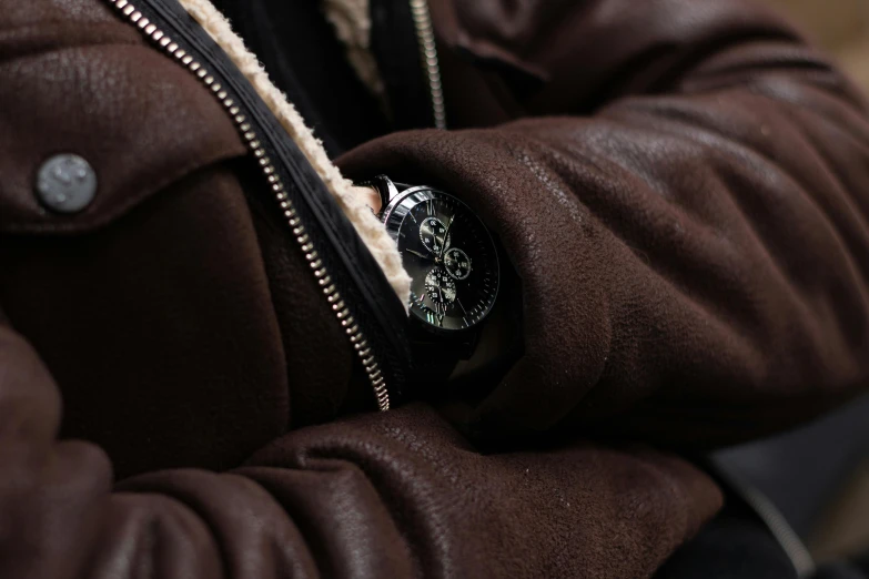 a person wearing a brown jacket and black jacket with a white wristwatch
