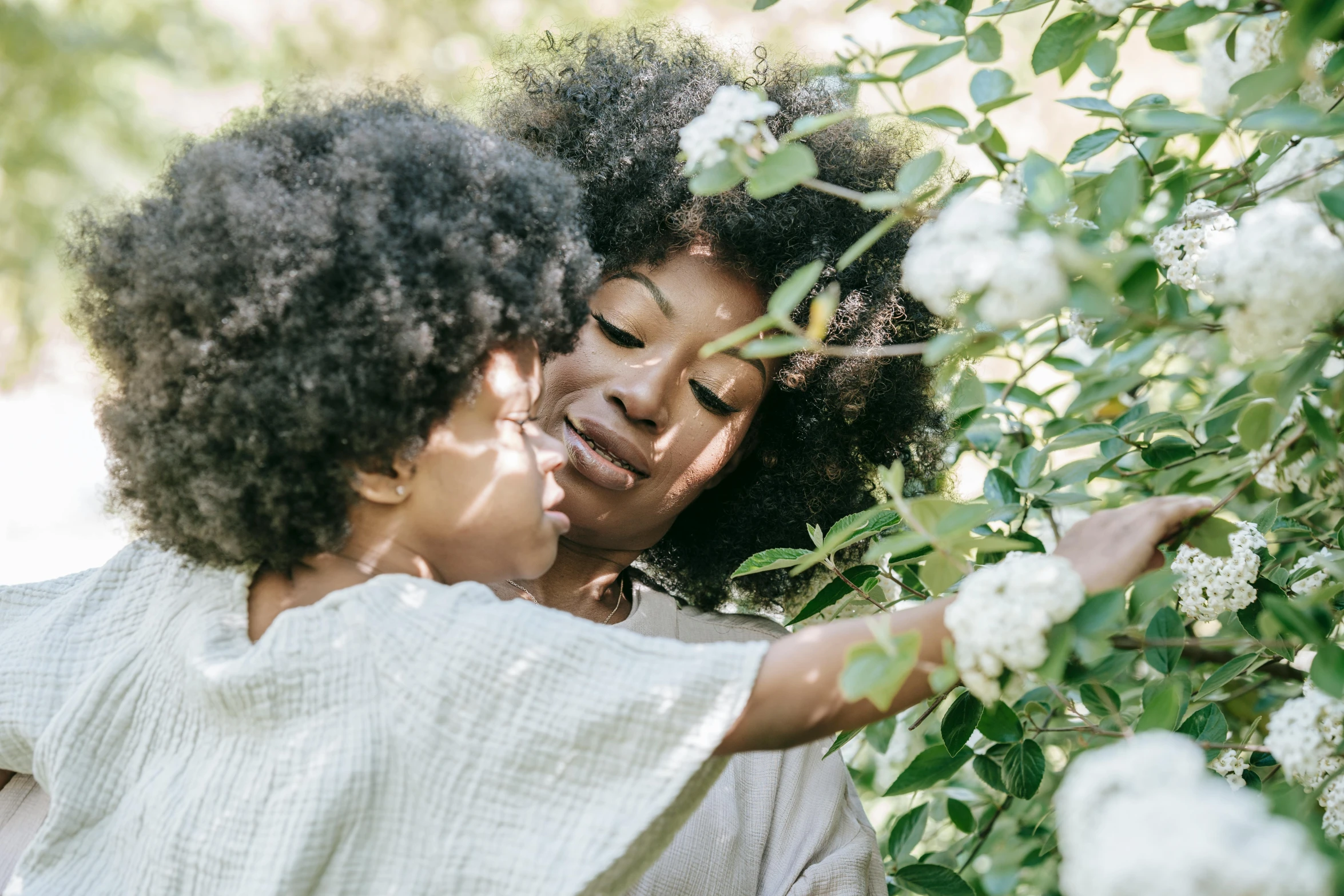 two women and a baby are picking flowers