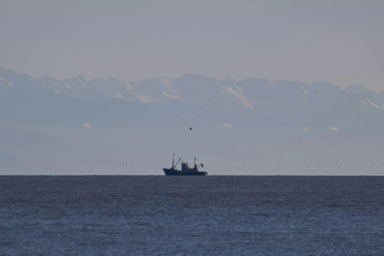 two boats floating on the water with mountains in the background