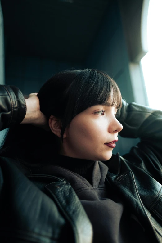 a woman wearing black jacket sitting next to a window