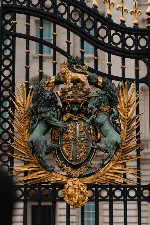 an ornate golden emblem surrounded by statues and a black fence