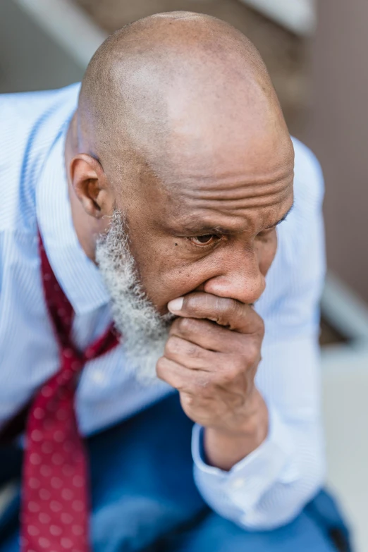 a man in blue shirt and tie holding his hands to his face