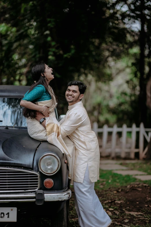 two young adults posing for pograph next to car