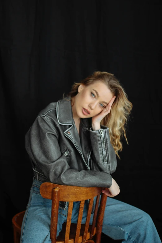 a blonde woman sitting on top of a wooden chair