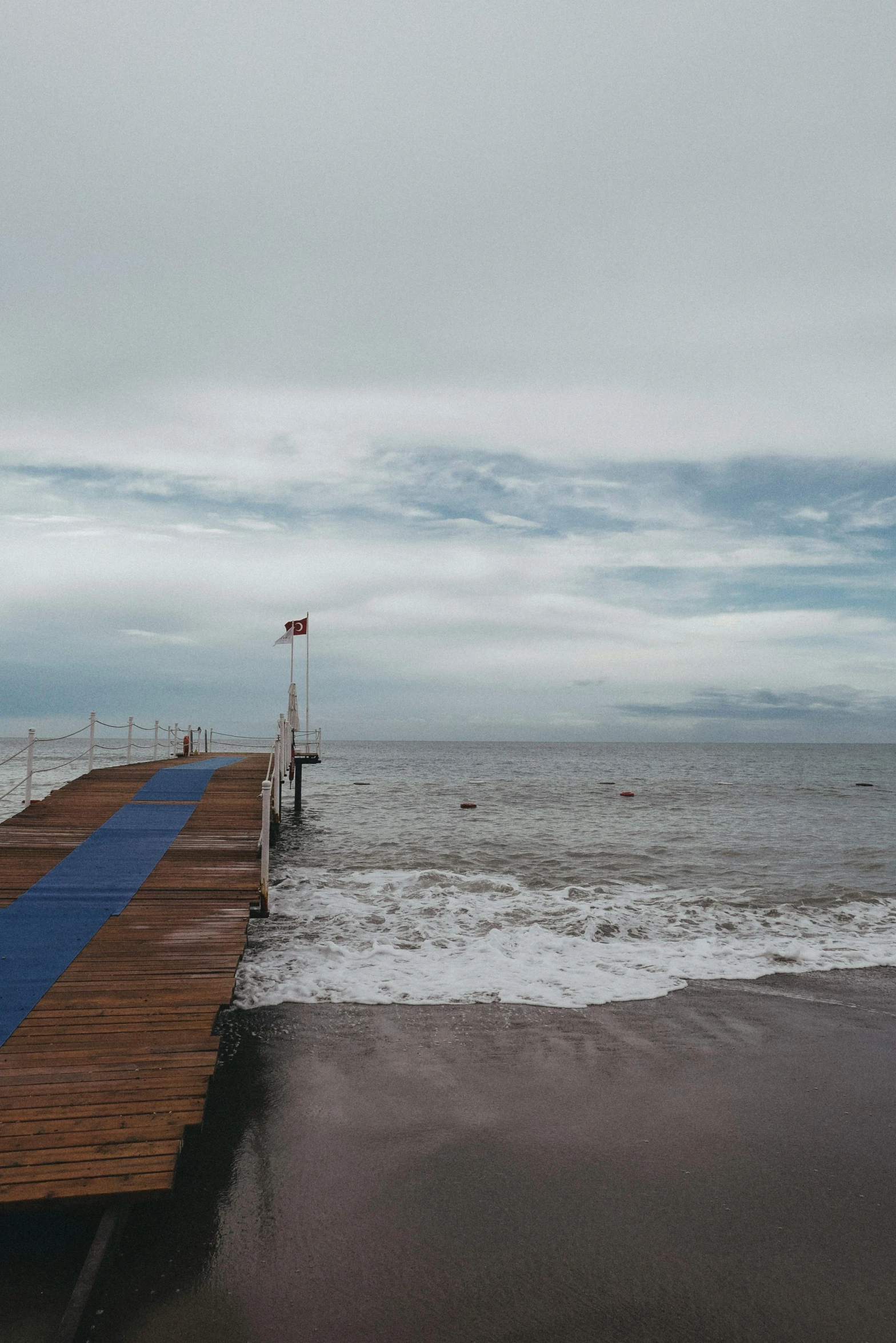 a wooden pier in the middle of a lake during a cloudy day