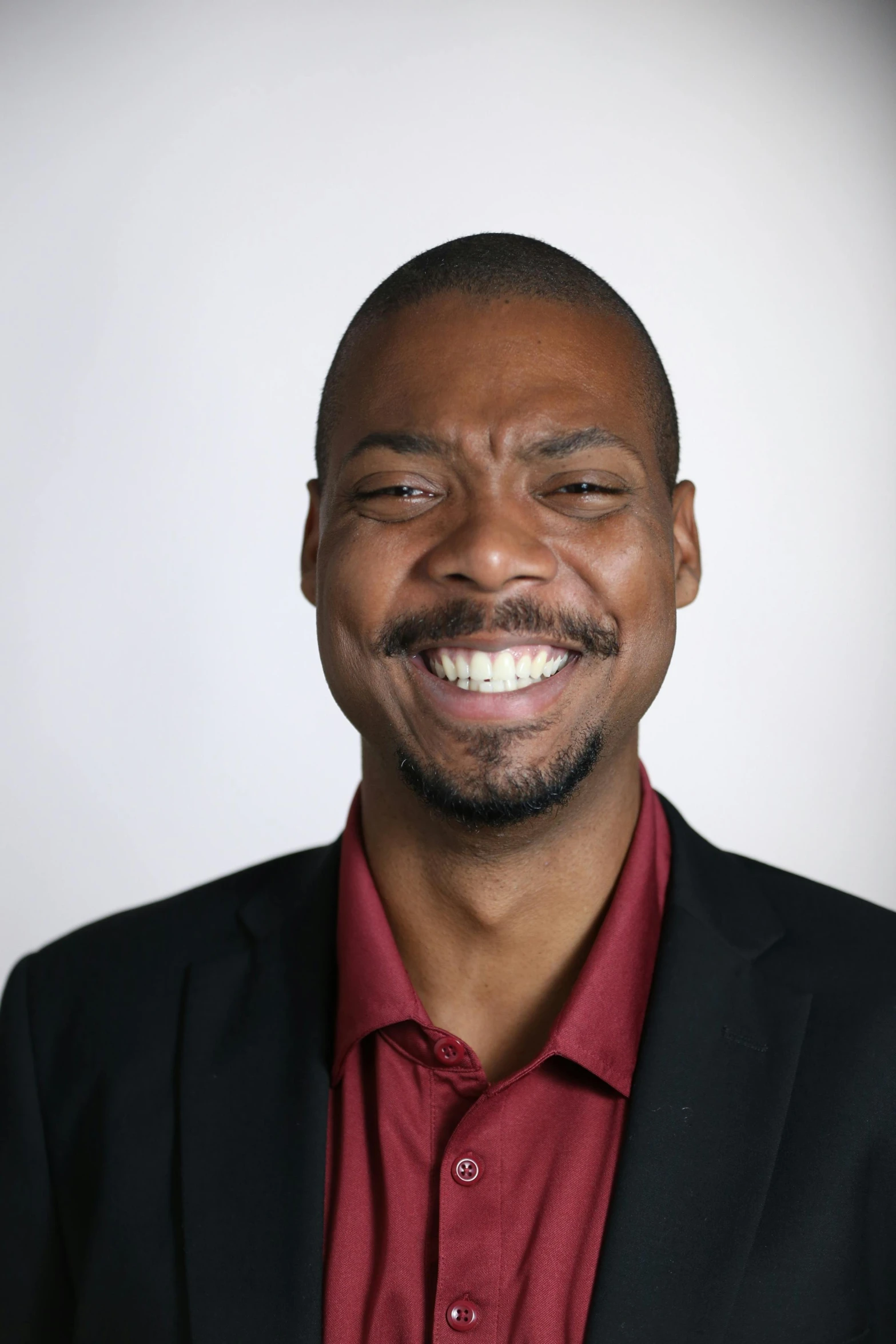 smiling man in red shirt with black jacket