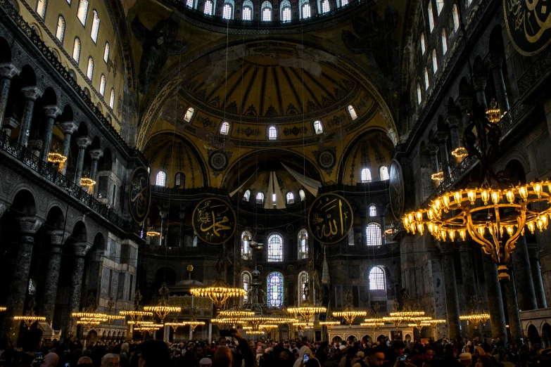 many people walk around inside the cathedral with chandeliers