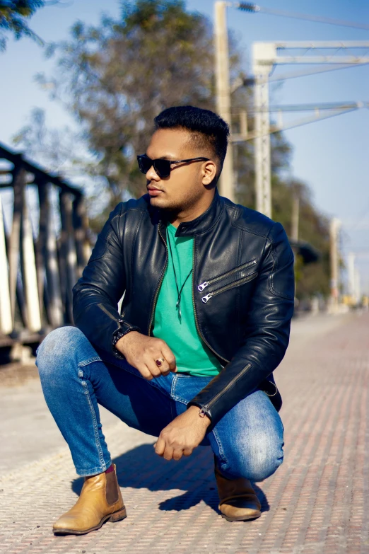 man in green shirt and jacket squatted on brick road