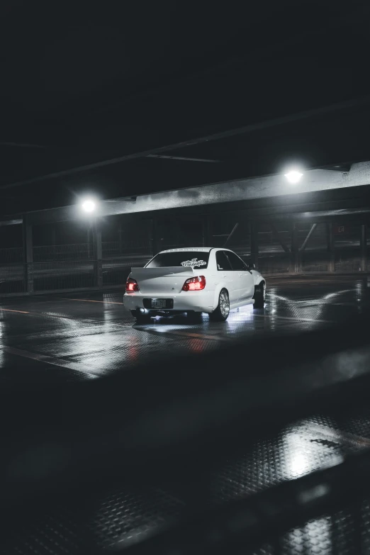 a white car is sitting in the rain at night