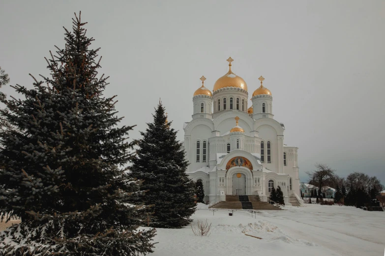 a snow covered church with golden domes and trees