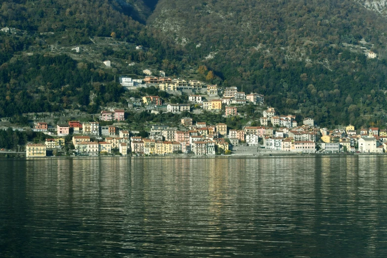 some mountains and houses on a hill next to a body of water