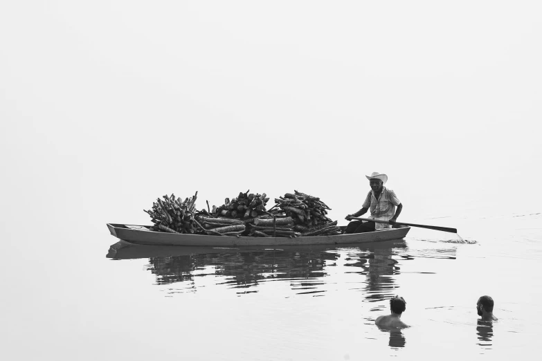 a man in a small canoe is rowing past some bananas